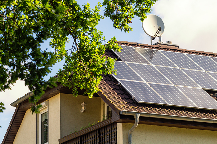 Photographie d'une maison avec un toit à 3 pans recouvert de panneaux solaires